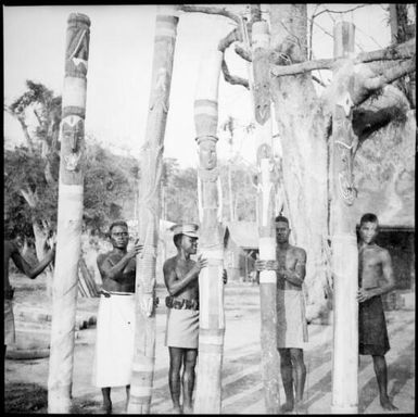 Five men each holding a carved totem pole, New Guinea, ca. 1936 / Sarah Chinnery