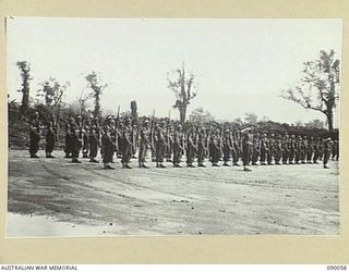 TOROKINA, BOUGAINVILLE. 1945-03-30. THE GUARD OF HONOUR COMPRISED OF MEMBERS OF 57/60 INFANTRY BATTALION, PRESENTING ARMS AT PIVA AIRSTRIP DURING THE ARRIVAL OF LORD AND LADY WAKEHURST AND LADY ..