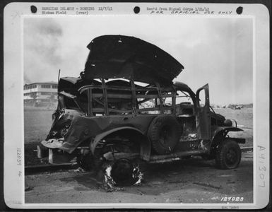 First Army Photos Of The Bombing Of Hickam Field, Hawaii, Dec. 7, 1941. Bombed Truck Still Bruning Off Hickam Parade Ground, 'F' Street At 11:15 A.M. (U.S. Air Force Number 122059AC)