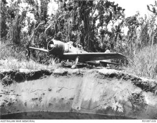 A DAMAGED AND ABANDONED JAPANESE MITSUBISHI A6M3 NAVY TYPE O MODEL 32 FIGHTER AIRCRAFT NEAR THE BUNA AIRSTRIP. THIS AIRCRAFT BELONGED TO THE JAPANESE NAVY'S 2ND AIR GROUP (582) FIGHTER SQUADRON, ..