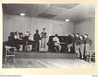 JACQUINOT BAY, NEW BRITAIN, 1945-08-12. SERGEANT R.P. BARLEE, A WELL KNOWN MELBOURNE ANNOUNCER OVER 3UZ, AT THE MICROPHONE IN STUDIO A, MAIN STUDIO OF THE NEW RADIO STATION 9AE OPERATED BY ..