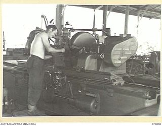 LAE, NEW GUINEA. 1944-06-09. SX30193 CRAFTSMAN W.T. JOY (1), AND WX15394 CORPORAL O.B. TERRY (2), MEMBERS OF THE 2/7TH ADVANCED WORKSHOP, GRIND A CRANKSHAFT ON A NORTON CRANKSHAFT GRINDER IN THE ..