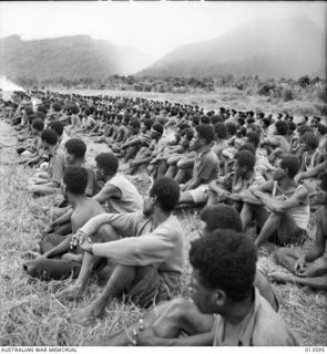 1942-11-19. NEW GUINEA. KOKODA. NATIVE CARRIERS OR PORTERS HAVE PLAYED A BIG PART IN THE ALLIED ADVANCE IN NEW GUINEA. NATIVE CARRIERS AT KOKODA LISTEN TO A SPEECH OF CONGRATULATIONS BY A HIGH ..