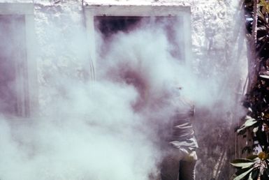 An Air Force security policeman prepares to enter a smoke-filled building being occupied by "terrorists." He is with a group of security police who are participating in anti-terrorist training being conducted by the 1ST Marine Brigade School