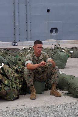 A US Marine Corps (USMC) personnel from the Combat Service Support Detachment 77 (CSSD-77) , waits on shore to embark the US Navy (USN) Amphibious Assault Ship USS TARAWA (LHA 1) at pier K-10, Pearl Harbor, Hawaii (HI). The TARAWA is participating in the amphibious exercise, Rim of the Pacific (RIMPAC) 2004. RIMPAC takes place every two years