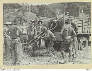 BOIKEN AREA, AITAPE-WEWAK SECTOR. 1945-04-28. MEMBERS OF 2/1 TANK ATTACK REGIMENT DIGGING A PIT FOR THE TRAIL WHILE MOUNTING A 75 MM PACK HOWITZER ON THE BACK OF A TRUCK TO ATTAIN A HIGH ELEVATION ..