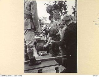 KAIRIRU ISLAND, NEW GUINEA. 1945-09-17. A MILITARY POLICEMAN GOING THROUGH PERSONAL BELONGINGS OF JAPANESE OFFICERS. THE OFFICER SHOWN IS EXPLAINING CONTENTS OF A LEATHER SATCHEL. THESE MEASURES ..