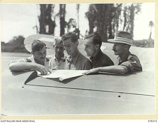 TOROKINA, BOUGAINVILLE ISLAND. 1945-01-15. PILOTS OF THE ROYAL NEW ZEALAND AIR FORCE BEING BRIEFED BY MAJOR DANIELS, AUSTRALIAN MILITARY FORCES, ARMY - AIR FORCE LIAISON OFFICER BEFORE TAKING OFF ..