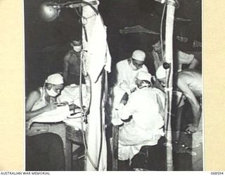 RAMU VALLEY, NEW GUINEA. 1943. AUSTRALIAN DOCTORS OPERATING ON WOUNDED SOLDIERS IN THE OPERATING THEATRE OF A MOBILE SURGERY UNIT IN THE FORWARD AREA