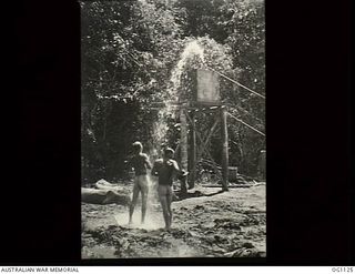AITAPE, NORTH EAST NEW GUINEA. 1944-06. TWO NAKED RAAF AIRMEN UNDER AN IMPROVISED A SHOWER AFTER A DAY'S WORK IN THE MUD OF THE JUNGLE. THEY ARE PROBABLY MEMBERS OF NO. 7 MOBILE WORKS SQUADRON RAAF ..