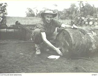 LAE-NADZAB, NEW GUINEA. 1944-07-20. A MEMBER OF THE 2ND CORPS SALVAGE UNIT DRAWING THE WATER FROM ON OF THE MANY 44 GALLON DRUMS OF USED ENGINE OIL COLLECTED BY PERSONNEL OF THE 39TH LINE OF ..