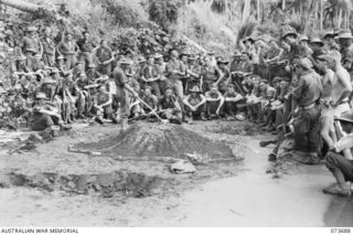 SARANG HARBOUR, NEW GUINEA. 1944-06-01. QX6239 MAJOR E G GREEN, OFFICER COMMANDING B COMPANY, 37/52ND INFANTRY BATTALION (18), USES A SAND MODEL TO OUTLINE TO HIS OFFICERS, NCOS AND MEN THE METHOD ..