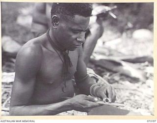 ALEXISHAFEN, NEW GUINEA. 1944-05-14. JOHNNY (1), A MADANG NATIVE, MAKING A RING FROM METAL SALVAGED FROM A JAPANESE ZERO FIGHTER AIRCRAFT. THE RINGS HE MANUFACTURES ARE TRADED TO SOLDIERS IN THE ..