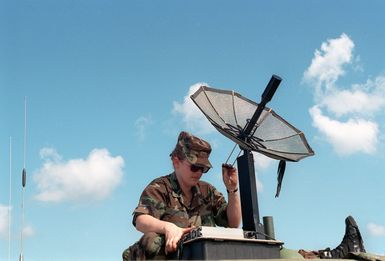 AIRMAN First Class (A1C) Pennington, US Air Force (USAF) 206TH Combat Communication Squadron, checks the coordinates on the International Maritime Satellite at Orote Point, Guam during Exercise TANDEM THRUST 99