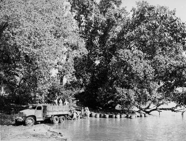 Scene showing New Zealand troops loading drums of benzine onto a truck from the water, Green Island, North Solomon Islands