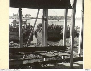 MADANG, NEW GUINEA. 1944-04-24. TROOPS OF THE 8TH INFANTRY BRIGADE LAND FROM AN LCM (LANDING CRAFT MECHANIZED) AFTER COMPLETING THE TRIP FROM SAIDOR. THE SHATTERED AREA HAD BEEN RECENTLY OCCUPIED ..