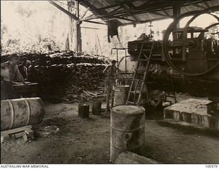 Lae, New Guinea. 1944-07-26. A boiler attendant stoking the steam engine at 2/3rd Forestry Company sawmill in the Busu Forest