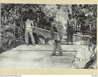 BOUGAINVILLE. 1945-04-18. 15 FIELD COMPANY ROYAL AUSTRALIAN ENGINEERS SAPPERS LAYING HEAVY DECKING ON TO BOX GIRDERS DURING THE CONSTRUCTION OF A 25-TON BRIDGE OVER DAWE CREEK. IDENTIFIED PERSONNEL ..