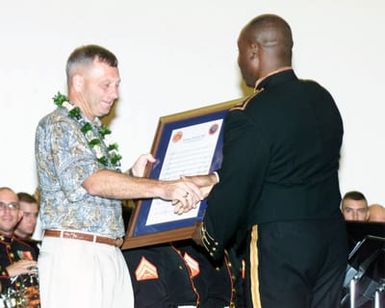 CHIEF Warrant Officer (COW3) Alexander K. Gray (right), USMC, Conductor for the Marine Forces Pacific Band presents an award to Brigadier General (BGEN) Jerry C. McAbee, USMC, Commanding General Marine Corps Base Hawaii (MCBH) during the Marine Corps Base Hawaii's Spring Concert