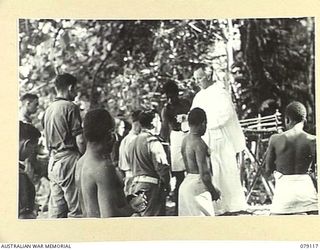 TSIMBA AREA, BOUGAINVILLE ISLAND. 1945-02-13. NX166853 CHAPLAIN T.O. ORMONDE, ASSISTED BY JOHN, A SAPIA MISSION BOY ADMINISTERING COMMUNION TO NATIVES AND TROOPS OF THE 31/51ST INFANTRY BATTALION