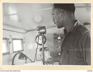 WEWAK, NEW GUINEA. 1945-10-29. SERGEANT N.S. BRAY AND SERGEANT E.C. PARRANT, MEMBERS OF 1 BROADCASTING STATION, AUSTRALIAN ARMY AMENITIES SERVICE, AT THE MICROPHONE OF RADIO STATION 9AJ WITH THEIR ..