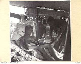 WIRUI BEACH, WEWAK AREA, NEW GUINEA. 1945-08-31. LANCE CORPORAL A.D. WARD, MAIN DRESSING STATION ORDERLY (2), TAKING THE TEMPERATURE OF PRIVATE J. PATTERSON (1), AT 2/1 FIELD AMBULANCE