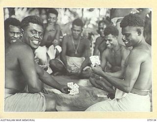 TSIMBA AREA, BOUGAINVILLE ISLAND. 1945-02-19. NEW GUINEA ADMINISTRATIVE UNIT (NGAU) NATIVES ENJOYING A FRIENDLY GAME OF CARDS ON PERAT WHILE AWAITING THE RETURN OF THE NEW GUINEA CONSTABULARY ..