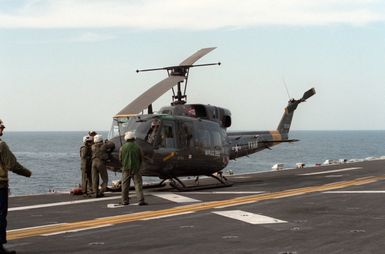 Crew members service a UH-1N Iroquois helicopter aboard the amphibious assault ship USS GUAM (LPH 9) during Exercise SOLID SHIELD '87