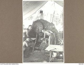 DUMPU, NEW GUINEA. 1943-11-05. COOKS OF THE 2/6TH AUSTRALIAN FIELD AMBULANCE USING A MAKESHIFT OVEN. SHOWN ARE: SX4745 SERGEANT E. S. LOWE (1); SX4686 CORPORAL COSMO BEENHAM OF STEPNEY, SA, (2); ..