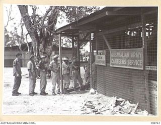 BORAM, NEW GUINEA. 1945-11-16. THE UNIT CANTEEN PERSONNEL AT 3 BASE SUB AREA, AUSTRALIAN ARMY CANTEENS SERVICE, QUEUE UP TO RECEIVE THEIR WEEKLY ISSUE OF DRY CANTEEN GOODS