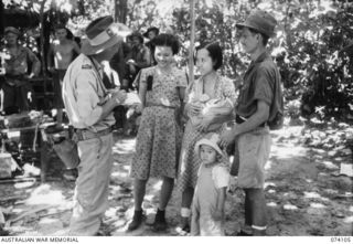 HANSA BAY, NEW GUINEA. 1944-06-16. MR F SIMPSON, OFFICIAL WAR CORRESPONDENT FOR THE AUSTRALIAN BROADCASTING COMMISSION, INTERVIEWING A CHINESE FAMILY WHO WERE MEMBERS OF A PARTY OF SOME 90 CHINESE ..