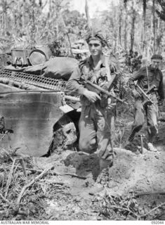 BOUGAINVILLE, 1945-05-16. PRIVATE F.J. PRIDMORE, 24 INFANTRY BATTALION (1), CAMOUFLAGED WITH LEAVES, MOVING OUT PAST A B SQUADRON 2/4 ARMOURED REGIMENT MATILDA TANK, ON A FIGHTING PATROL IN D ..