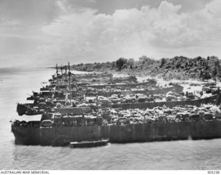 CAPE GLOUCESTER, NEW BRITAIN. 1943-12. SEVEN LANDING SHIPS, TANK (LSTS), OF THE US NAVY UNLOAD MEN AND EQUIPMENT ONTO THE BEACH. THE FOUR VESSELS NEAREST THE CAMERA ARE LST-463, LST-468, LST-475 ..