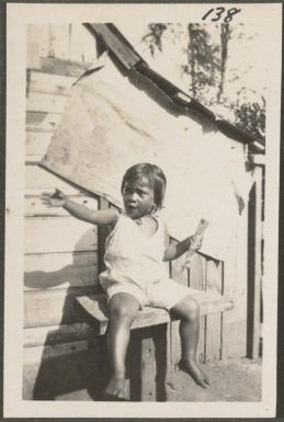 Malay child sitting on steps, Rabaul, New Britain Island, Papua New Guinea, approximately 1916