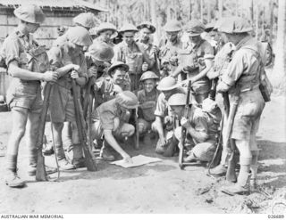 A fighting patrol from the 2/10th Australian Infantry Battalion studies maps and plans before setting off into the jungle in search of Japanese still in the vicinity. Identified standing, second ..