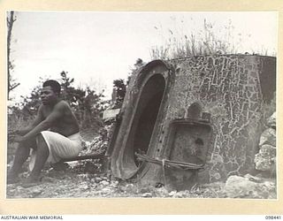 KAVIENG, NEW IRELAND. 1945-10-19. A JAPANESE PILLBOX CONSTRUCTED FROM A WARSHIP GUN TURRET ON THE SHORE AT KAVIENG. AN AUSTRALIAN NEW GUINEA ADMINISTRATIVE UNIT ADMINISTRATIVE HEADQUARTERS IS BEING ..