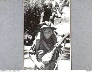 KAIAPIT, NEW GUINEA. 1943-09-25. QX33433 PRIVATE R.P. KING OF THE 2/14TH AUSTRALIAN INFANTRY BATTALION GIVING A NATIVE BOY A RIDE ON HIS SHOULDERS