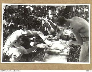 FINSCHHAFEN, NEW GUINEA. 1944-01-01. COOKS OF HEADQUARTERS 9TH DIVISION PREPARING A CHRISTMAS TURKEY FOR THE OVEN. IDENTIFIED PERSONNEL ARE: QX12574 SERGEANT C. J. PARRY (1); NX166431 PRIVATE S. F. ..