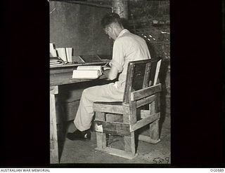 VIVIGANI, GOODENOUGH ISLAND, PAPUA. C. 1944. CORPORAL R. J. MCCREADY RAAF OF MT LOFTY, SA, IN ONE OF THE FIRST CHAIRS MADE ON GOODENOUGH ISLAND. THE FINISH INDICATES THAT IT WAS PROBABLY MADE FOR A ..