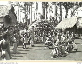 LAE, NEW GUINEA. 1944-11-27. NX95472 LIEUTENANT F.S. WOOD, PHOTOGRAPHER, MILITARY HISTORY SECTION, TAKING PHOTOGRAPHS OF SOME OF THE NATIVE INHABITANTS OF BUTIBUM VILLAGE. THIS VILLAGE HAS BEEN ..