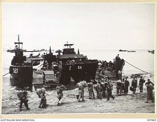 BORAM BEACH, NEW GUINEA. 1945-10-13. THE FIRST BATCH OF TROOPS TO LEAVE THE WEWAK AREA UNDER THE PRIORITY DEMOBILISATION SCHEME WERE MEMBERS OF 6 DIVISION. SHOWN THE TROOPS MOVING ALONG THE BEACH ..