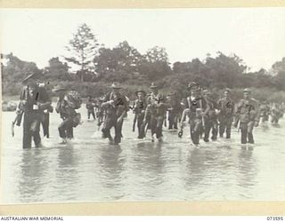 Forward troops of the 35th Infantry Battalion cross the river during their advance up the coast towards Wewak accompanied by two unknown members of C Company, 533rd Engineer Boat and Shore ..