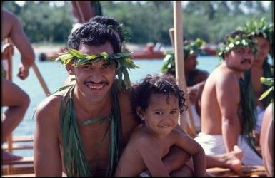 Man wearing wreath and necklaces, and child