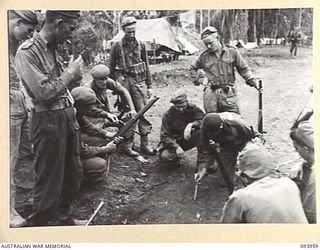 ULUPU, NEW GUINEA, 1945-07-10. LT K.S. MCKENZIE OF 11 PLATOON, B COMPANY, 2/5 INFANTRY BATTALION EXPLAINING BY MEANS OF THE DIAGRAM ON THE GROUND THE TACTICS AND LINE OF ADVANCE BEFORE THE MEN GO ..