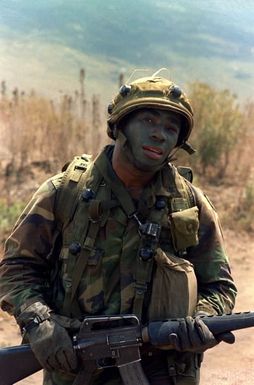 A member of the 1ST Bn., 35th Inf., 25th Inf. Div., moves toward "enemy' held positions after exiting a UH-1 Iroquois helicopter during an annual training exercise. He is wearing the MILES (multiple integrated laser engagement system) and is armed with an M-16A1 rifle