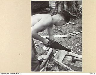 CAPE PUS, NEW GUINEA. 1945-11-03. LANCE CORPORAL FALLSHAW, 2/2 INFANTRY BATTALION, PREPARING THE MOULD OF A SKIFF TO BE ENTERED IN THE COMING CARNIVAL