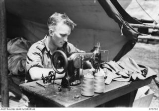 SIAR-NAGADA, NEW GUINEA. 1944-09-08. Q27988 SERGEANT L.H. GOODWIN, TAILOR, 61ST INFANTRY BATTALION "THE QUEENSLAND CAMERON HIGHLANDERS," REPAIRING A UNIFORM