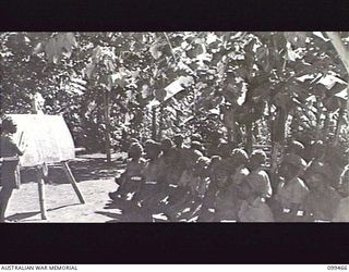 RABAUL, NEW BRITAIN, 1945-12-17. A NATIVE SOLDIER OF 1ST NEW GUINEA INFANTRY BATTALION GIVING A LECTURE TO FELLOW MEMBERS OF HIS UNIT UNDER THE EDUCATION SCHEME ORGANISED BY THE AUSTRALIAN ARMY ..