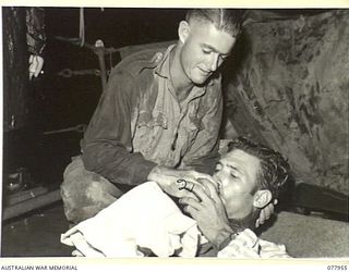 AT SEA. 1944-12-30 - 1945-01-01. VX133470 PRIVATE C. YOUNG, MEDICAL ORDERLY (1) GIVING A DRINK TO WX10863 CRAFTSMAN R. FERNIHOUGH, 2/137TH ARMY WORKSHOPS SOON AFTER BOARDING THE RAN VESSEL, ML802 ..