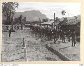 TOROKINA, BOUGAINVILLE. 1945-04-22. MAJOR GENERAL C.H. SIMPSON, SIGNAL OFFICER- IN- CHIEF (1), TAKING THE SALUTE DURING THE MARCH PAST OF 1 COMPANY, HEADQUARTERS B CORPS SIGNALS, LED BY MAJOR C. ..